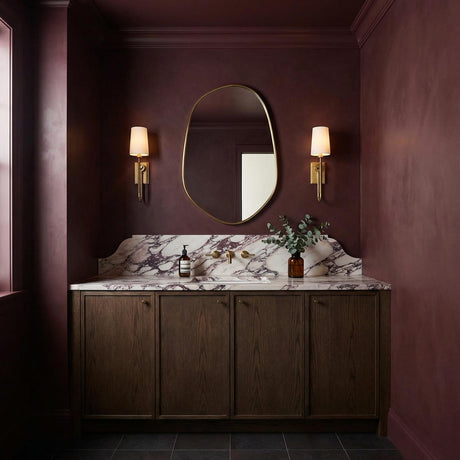 Pratt Single Wall Sconce 21", Aged Brass linear Wall Sconce in a Transitional Bathroom with a purple marble backsplash and wood vanity.