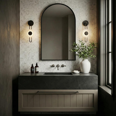 Quella LED Wall Sconce 18", Old Bronze and Piastre Glass geometric wall sconce in a Modern Bathroom with an arched mirror and stone vanity.