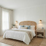 Delora Patina Brass woven wall sconce in a Coastal Bedroom with a rattan headboard and light wood nightstands.