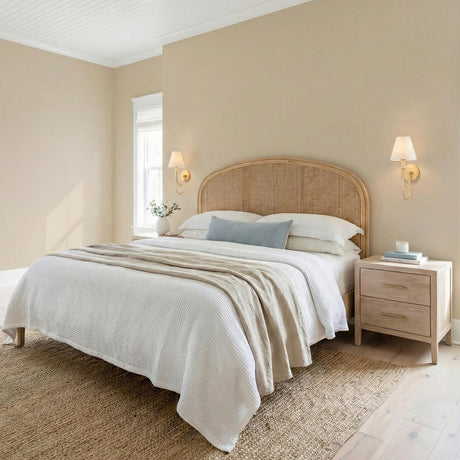 Velora Wall Sconce, Gold curved arm Wall Sconce in a Coastal Bedroom with a woven cane headboard.