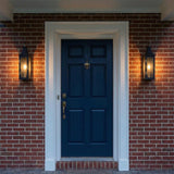 Yorktown Black geometric outdoor wall light in a Colonial outdoor entryway with a red brick wall and navy blue door.