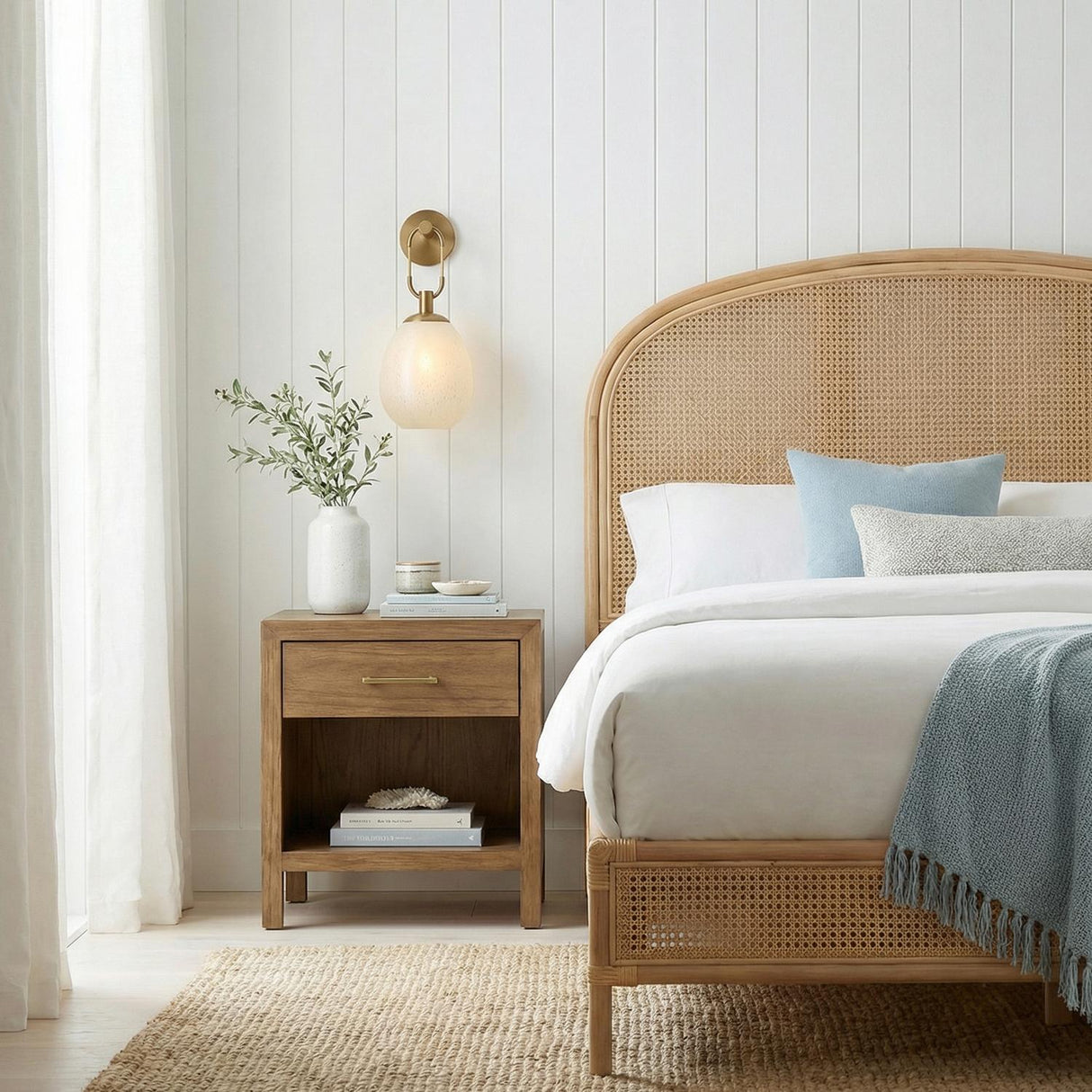 Orly Wall Sconce 17", Patina Brass and Seeded Cloud Glass globe wall sconce in a Coastal Bedroom with a cane headboard and oak nightstand.