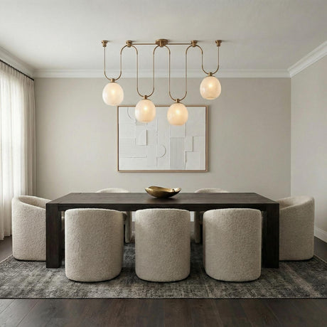 Orly 4 Light Linear Chandelier 58", Patina Brass and Seeded Cloud Glass globe Chandelier in a Contemporary Dining Room with boucle chairs.