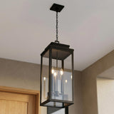 A modern entryway with the matte black Trevor Outdoor Hanging Light, Extra Large 28", Black lantern featuring clear glass panels over the wood door entry.
