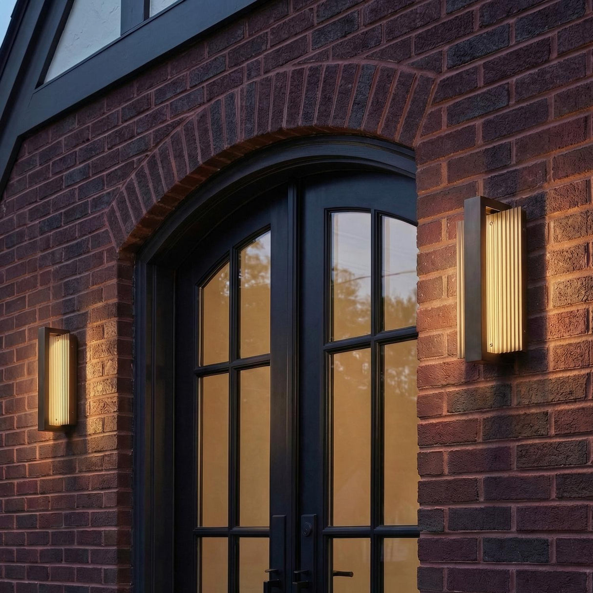 Zenith Bronze 12" linear Outdoor Wall Light in a Traditional Outdoor entryway with a red brick wall and arched black doors.