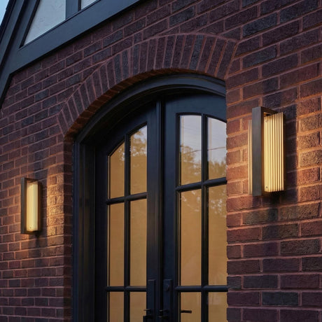 Zenith Bronze 12" linear Outdoor Wall Light in a Traditional Outdoor entryway with a red brick wall and arched black doors.