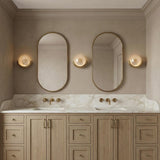 Soleil LED Wall Sconce 11", Antique Brass globe Wall Sconce in a Transitional Bathroom with a white marble double vanity.