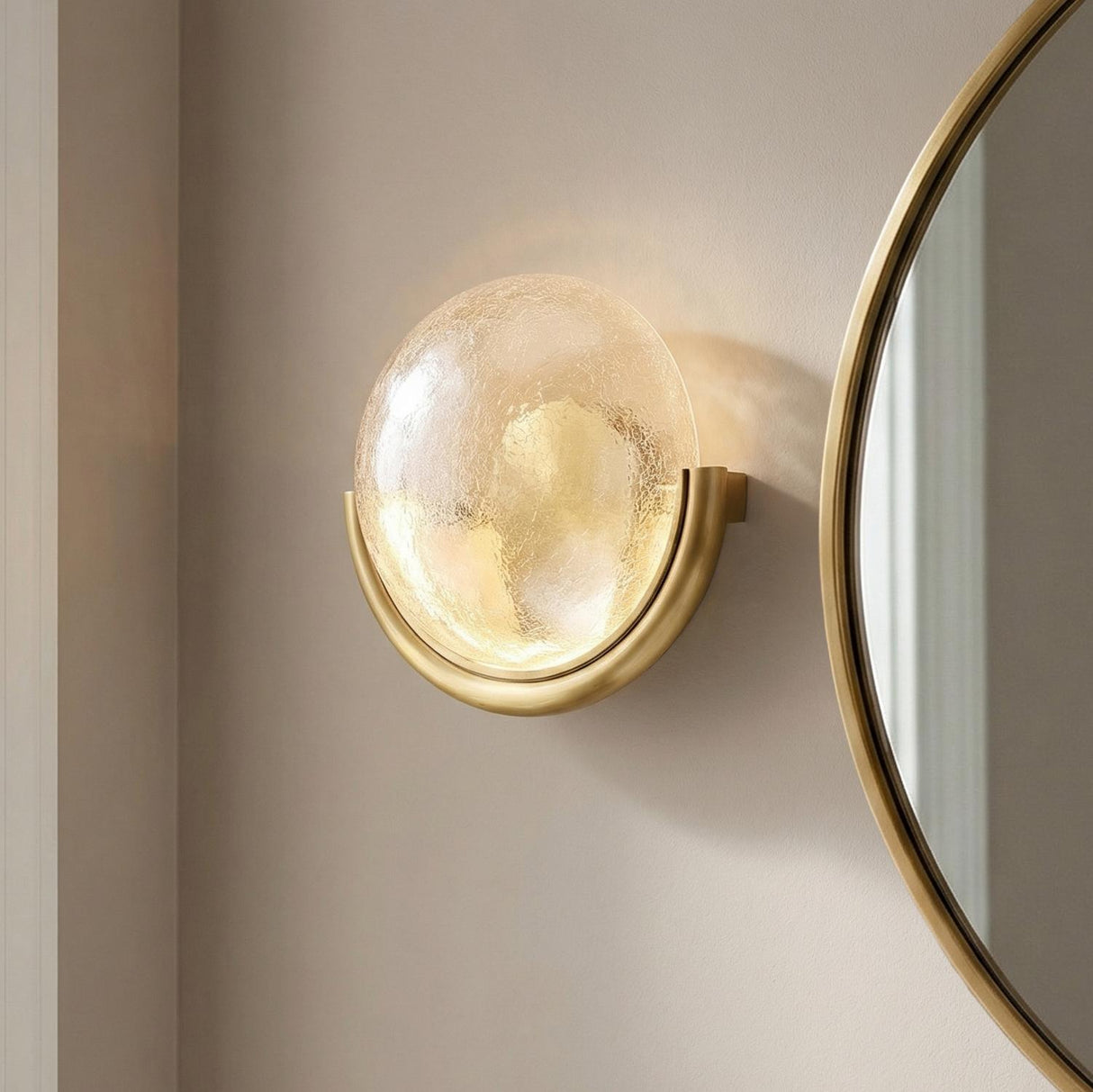 A contemporary hallway with a Soleil LED Wall Sconce 11", Antique Brass featuring crackled glass and a crescent base mounted beside a large round mirror.