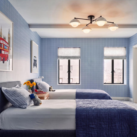 A modern bedroom featuring the Hanley 4 Light Flush Mount in matte black and ivory crackle ceramic centered above twin beds with blue grid wallpaper.