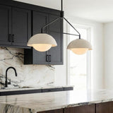 A kitchen features the Hanley 2 Light Linear Pendant 32", matte black and ivory crackle ceramic over a marble island with black cabinets and a marble backsplash.