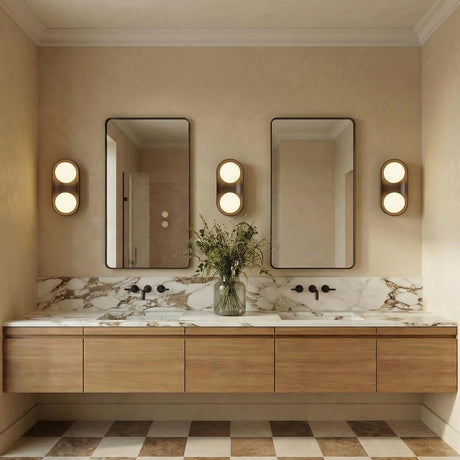 A contemporary bathroom featuring three matte black ceramic Hanley wall sconces with brass accents flanking two mirrors above a veined marble countertop and floating wood vanity.