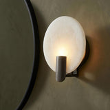 Othello Wall Sconce 9", Bronze and Onyx geometric Wall Sconce in a Contemporary Bathroom with a black circular mirror and olive wall.