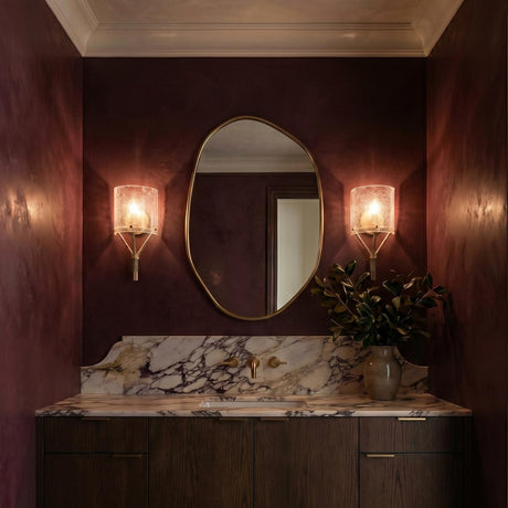A contemporary bathroom featuring the Nadine Wall Sconce in gold and clear seeded glass flanking an organic mirror above a purple-veined marble vanity and dark wood cabinets.