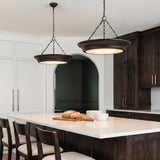 A transitional kitchen with two aged iron saucer pendants hanging over a white quartz island featuring dark wood cabinets and white perimeter cabinetry.