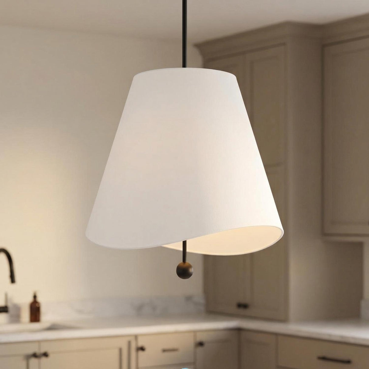A transitional kitchen features the Jada Large Conical Pendant 24", Matte Black with a white linen shade over the island, complemented by taupe cabinets and marble countertops.
