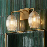 Fiora 2 Light Vanity 16", Modern Brass globe Vanity in a Contemporary Bathroom with green tiled walls and a brass mirror.