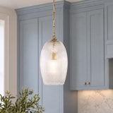 A transitional kitchen features the Fiora Pendant in modern brass with a ribbed glass shade suspended over an island with blue shaker cabinets.