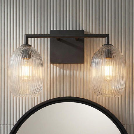 Fiora 2 Light Vanity 16", Aged Iron scalloped Vanity in a Contemporary Bathroom with a round black mirror and fluted wall tile.