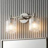 A contemporary bathroom featuring the Lathan 2 Light Vanity 15", Polished Nickel with ribbed glass shades mounted above a mirror on a vertically fluted gray tile wall.
