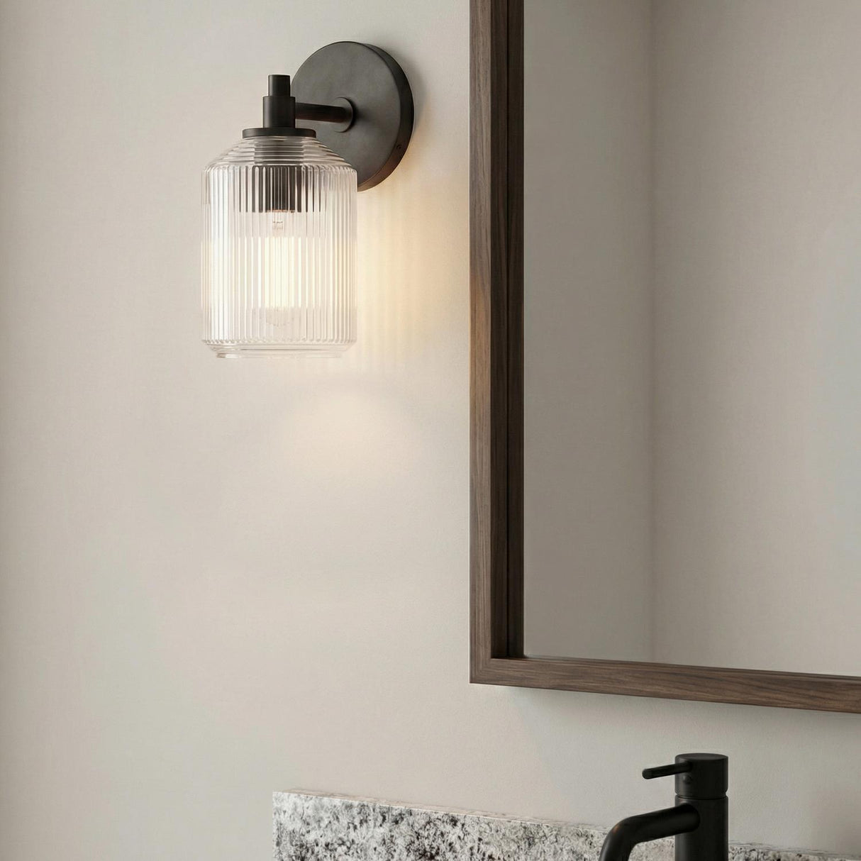 Lathan Wall Sconce 9", Aged Iron ribbed glass Wall Sconce in a Modern Farmhouse Bathroom with a wood framed mirror.