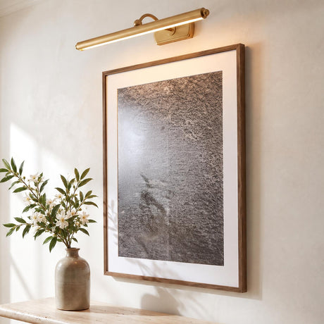 A modern living room features the Bria LED Picture Light in modern brass mounted above a framed art print set over a console table.