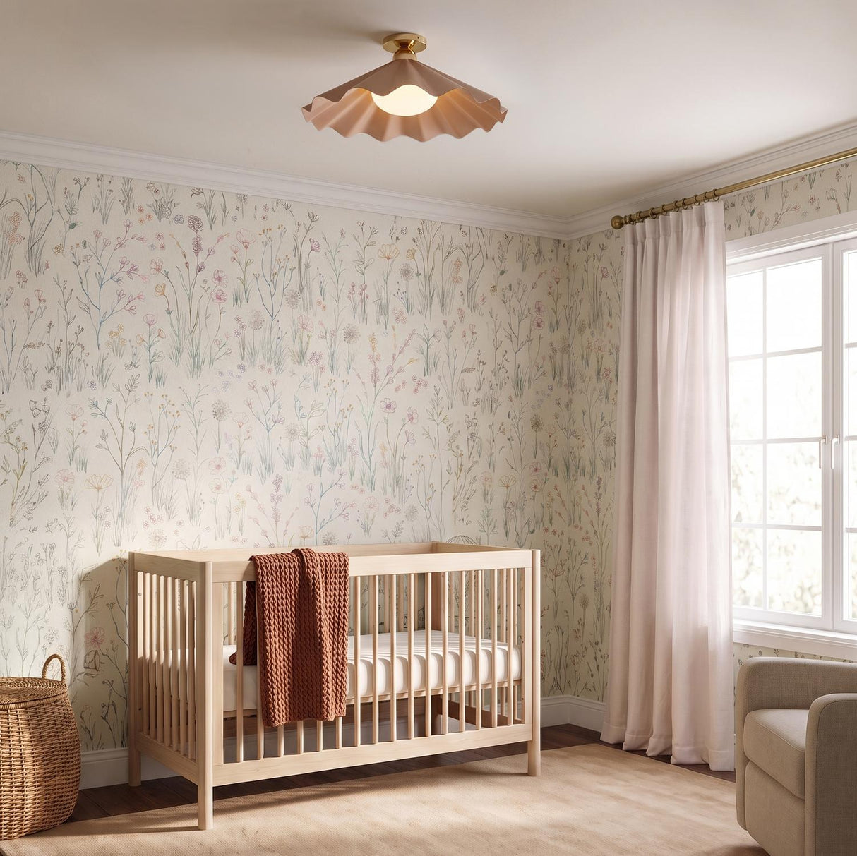 A cottage bedroom with a blush and brushed brass semi-flush mount fixture installed on a standard ceiling center above a light wood crib and floral wallpaper.