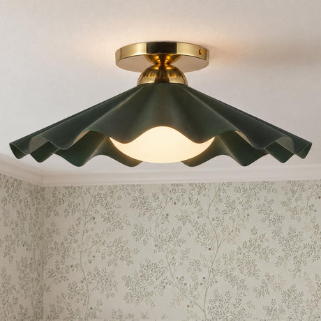 A cottage bedroom features the Babette Medium Semi-Flush 16-inch, Hunter Green and Brass light fixture with a scalloped shade set against delicate botanical wallpaper.