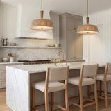 A transitional kitchen features two Pascal Large Pendant 22", Jute, Rattan and Aged Brass fixtures over a white marble waterfall island under a shiplap ceiling.
