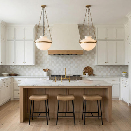 Capella 19" Patina Brass and Milk Glass globe pendant in a Modern Farmhouse Kitchen with a white marble island and oak stools.