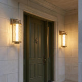 Catalina LED Outdoor Wall Light, Large 23", Patina Brass geometric wall sconce in a Transitional Outdoor entryway with a green door.