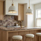 A transitional kitchen features two Patrice Medium Pendant 15", Matte White and Aged Brass fixtures hanging over a wood island with brown marble countertops and light cabinets.