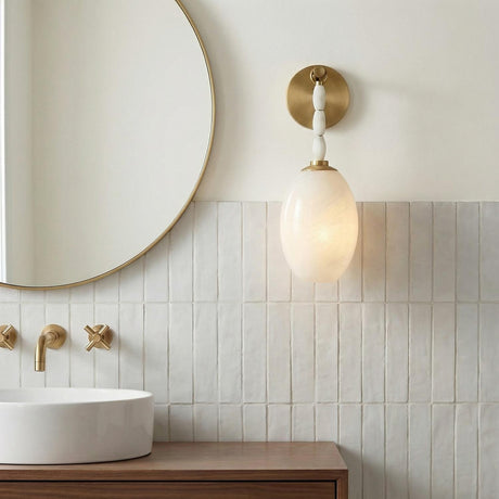 A contemporary bathroom featuring the Helena Wall Sconce in aged brass and cloud glass with alabaster accents mounted on a white vertically tiled wall above a wood vanity.