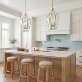 A transitional kitchen featuring two light blue and aged brass Ravenna Large Pendants hanging over a white marble island with rattan stools and a blue tile backsplash.