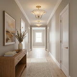 A transitional foyer with two Marcelle semi-flush mounts in aged brass and linen along the ceiling above a wood console and light oak flooring.