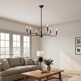 A transitional living room with the Harwick 6 Light Chandelier in an aged iron finish hanging above a beige sofa and white French doors.