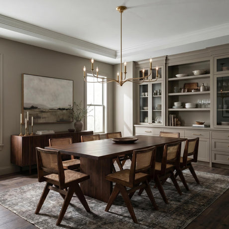 A transitional dining room featuring the Harwick 8 Light Chandelier 42", Gilded Brass centered over a dark wood table with cane chairs and built-in beige cabinetry.