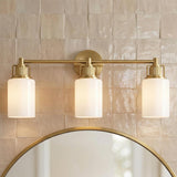 Claxton 3 Light Vanity 24", Modern Brass geometric Vanity in a Modern Farmhouse Bathroom with a round mirror and textured tile.