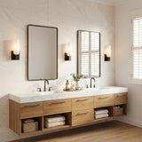 A modern bathroom featuring three Vesper Wall Sconce 12", Aged Iron fixtures with white glass shades flanking rectangular mirrors over a marble countertop and oak vanity.
