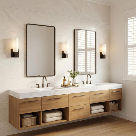 A modern bathroom featuring three Vesper Wall Sconce 12", Aged Iron fixtures with white glass shades flanking rectangular mirrors over a marble countertop and oak vanity.
