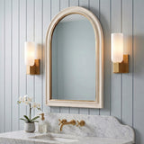 A transitional bathroom with two Vesper Wall Sconce 12", Modern Brass fixtures with frosted glass shades flanking an arched mirror above a marble vanity.