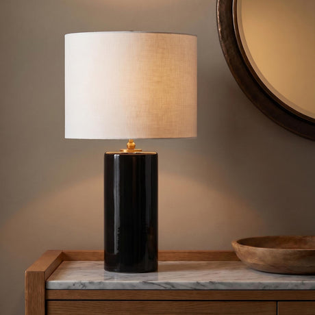 A contemporary entryway featuring the Joleigh Table Lamp 26", Glossy Black with a white linen shade on a marble top console table beside a round wall mirror.