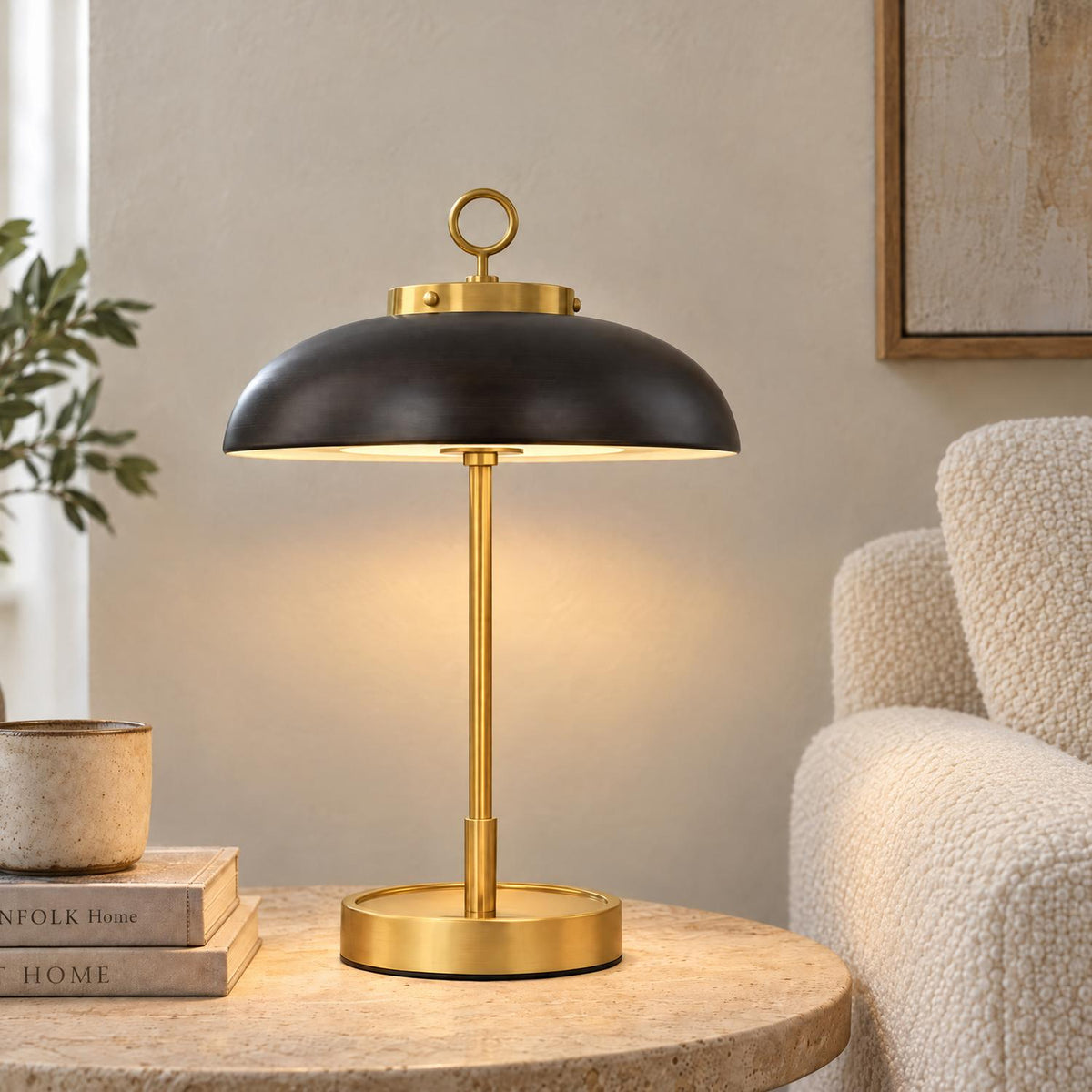 A transitional living room features the Dax Rechargeable Table Lamp with a distressed bronze dome shade and aged brass base on a travertine side table.