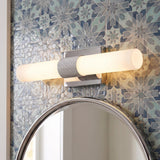 A contemporary bathroom featuring the Ramsey LED Vanity Light 18", Chrome with a polished chrome finish and frosted glass tube over a round mirror with blue patterned tile.