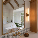 A modern farmhouse bathroom with the Ramsey LED Vanity Light 18", Satin Brass beside a large gold-framed mirror overlooking a soaking tub and vaulted wood-beamed ceilings.