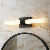 A modern bathroom with the Ramsey LED Vanity Light 30", Matte Black in a matte black finish with ribbed glass over a round mirror and marble wall.
