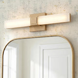 A contemporary bathroom featuring a Wendell LED Vanity Light 18", Satin Brass mounted above a gold arched mirror on textured wallpaper with subtle gold flecks.