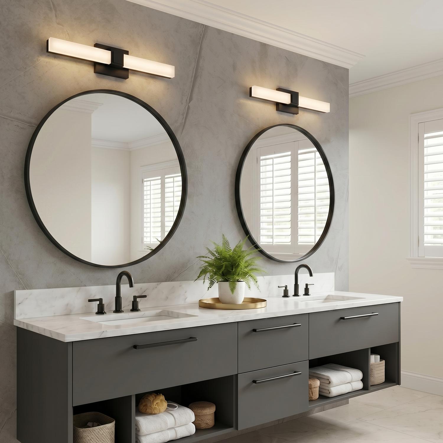 A contemporary bathroom with two matte black Wendell LED Vanity Lights mounted above round mirrors and a white marble countertop with a charcoal floating vanity.