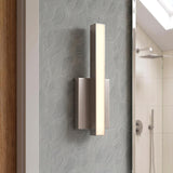 A modern bathroom with a Garrison LED Wall Sconce 13", Brushed Nickel mounted on gray textured wallpaper beside a mirror reflecting a sloped ceiling and shower.