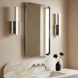 A modern bathroom with two polished chrome Garrison LED Wall Sconce 13", Chrome fixtures flanking a rounded rectangular mirror over a marble vanity and integrated backsplash.