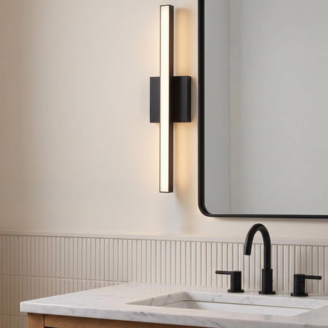 A modern bathroom with a Garrison LED Vanity Light 24", Matte Black, mounted vertically beside a matching mirror above a marble countertop and black faucet.